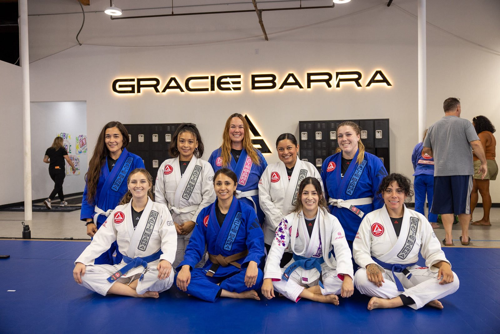 The Gracie Barra Ventura women's class smiling together on the mats under the academy sign